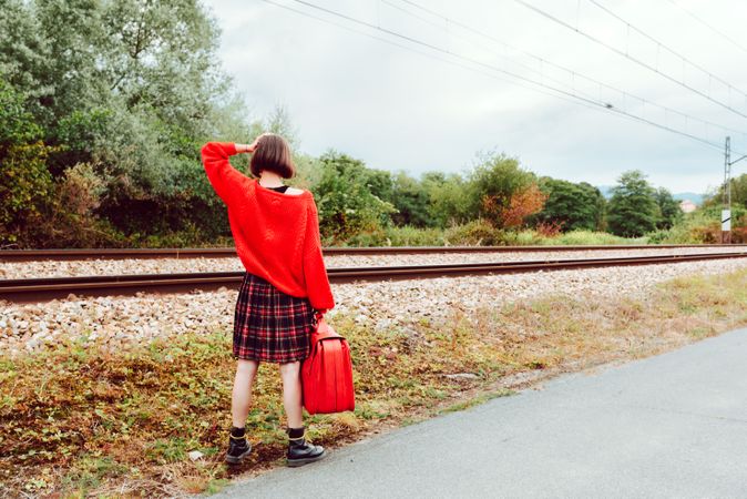 Woman looking at approaching modern train on railroad