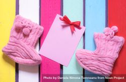 Flat lay of knitted booties and a blank pink paper note 41Oo80