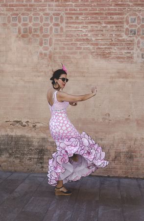 Passionate woman in flamenco dress dancing on street