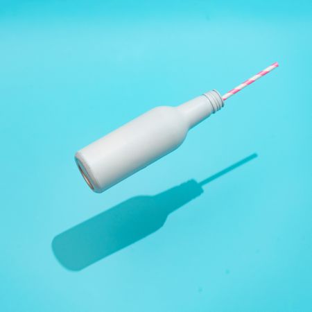 Bottle with straw on bright blue background