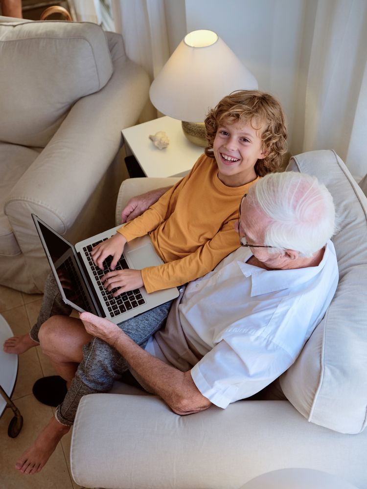 Smiling boy with grandfather using laptop