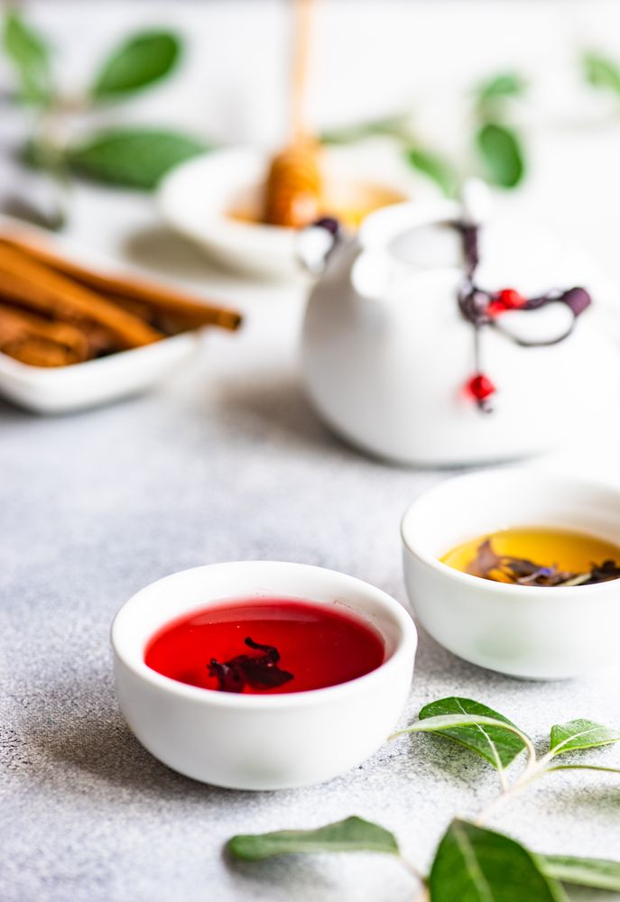 Red tea in small cup with tea pot in background