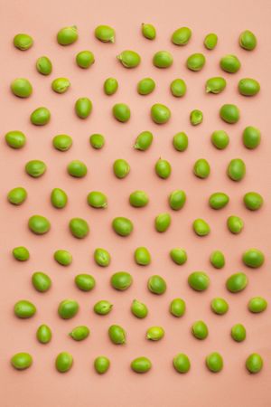Set of peas placed orderly on salmon colored background