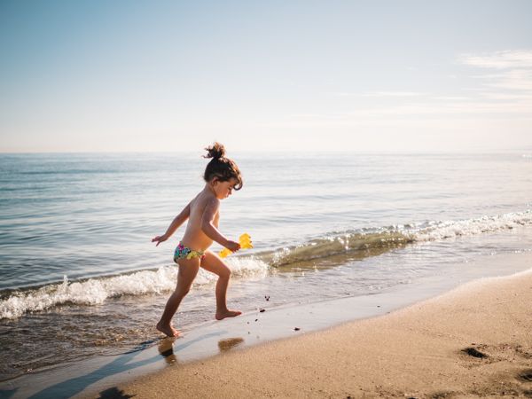 Toddler girl walking on sandy beach