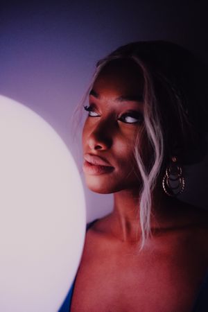 Black adult woman with illuminated balloon in darkness looking at camera