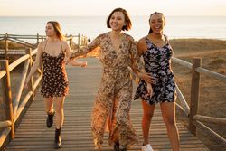 Three smiling woman walking on coastal pedestrian walkway