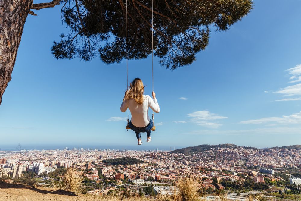 Young female swinging over the city
