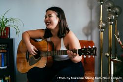 Young multiracial woman laughing while holding her guitar 56GWx4