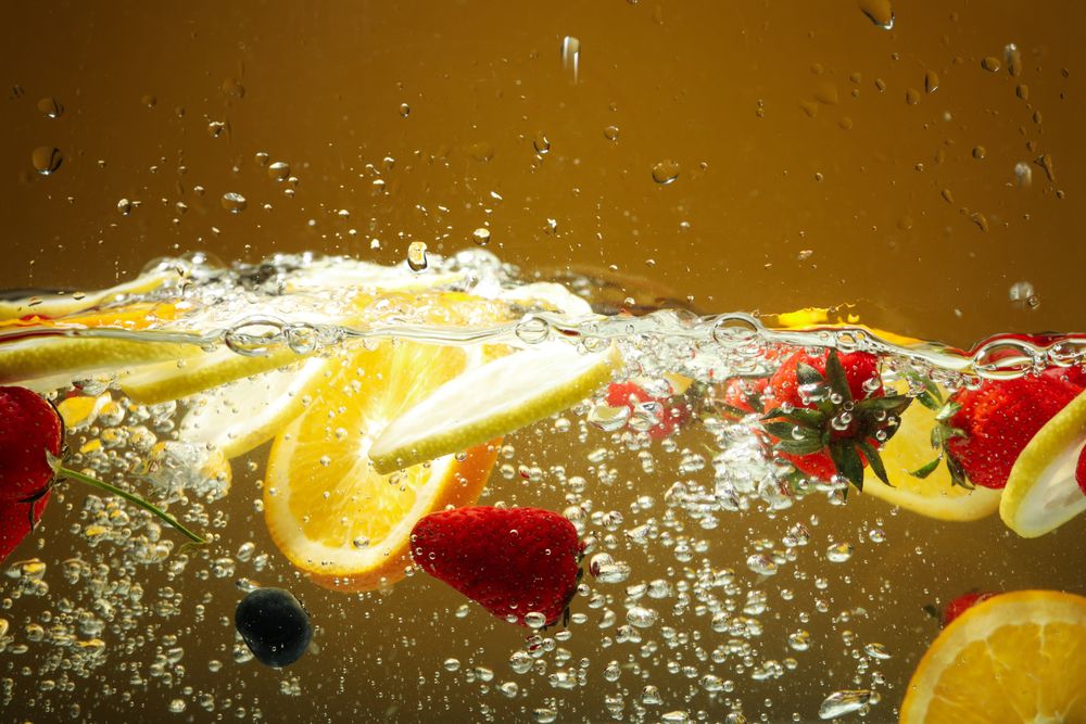 Side view of citrus slices and strawberries suspended in water
