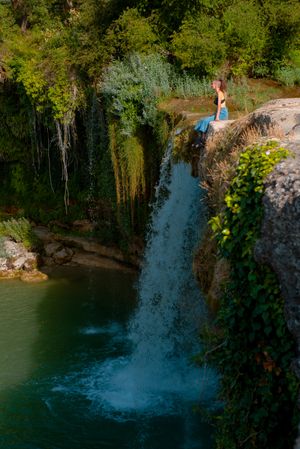 Young woman sitting near waterfall