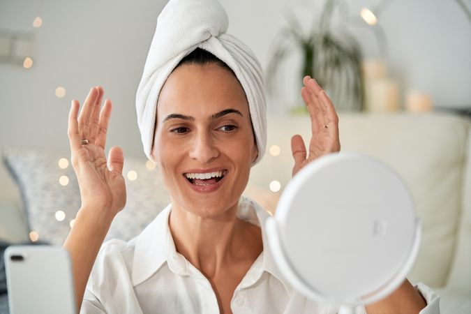 Cheerful woman looking at mirror with smartphone