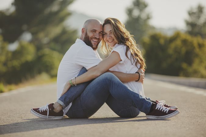 Affectionate couple embracing close sitting on rural road