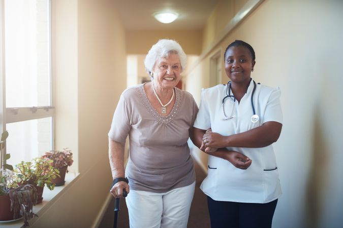 Caring female nurse assisting a older patient to walk