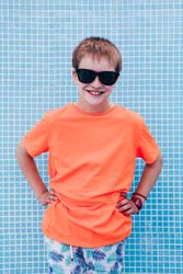 Happy boy in sunglasses against tiled wall