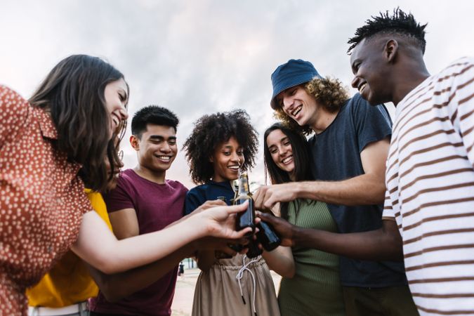 Group of multi-ethnic friends celebrating together with beer outside