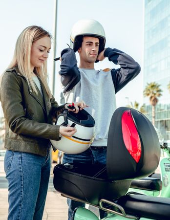 Woman and man regulating motorcycle helmets