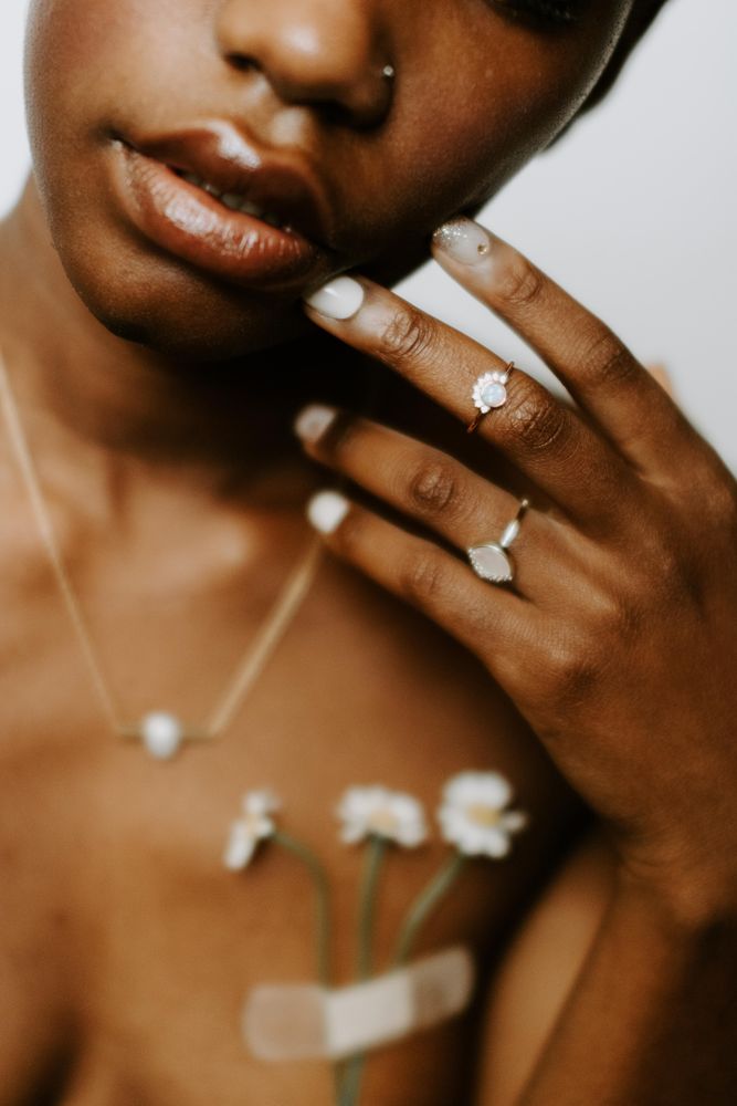 Woman with light flower and band aid on chest wearing pearl necklace
