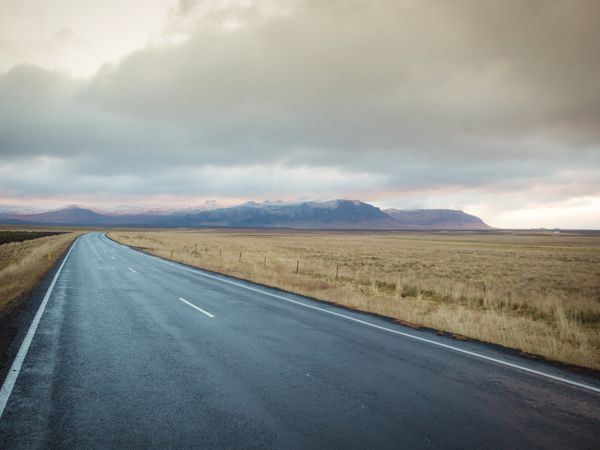 Road running between fields and mountains