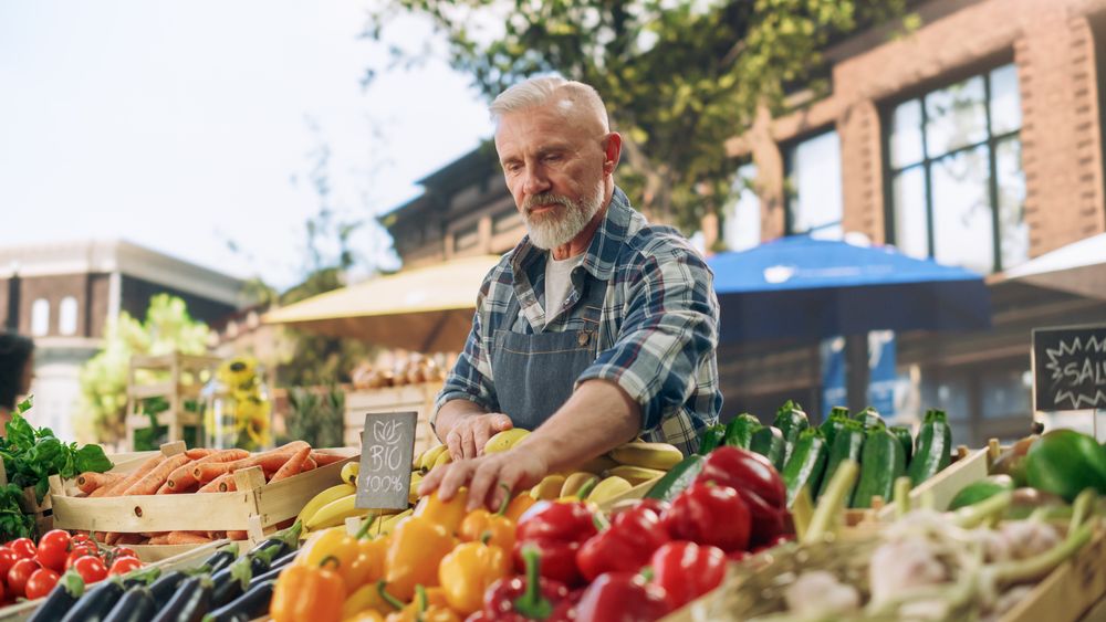 Portrait of a Mature Street Vendor Working at a Farmers Market Stall with Fresh Organic Agricultural Products.