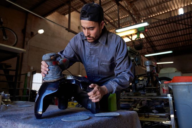 Male mechanic repairing motorbike in big garage