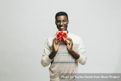 Smiling Black man holding gold box with red bow below his face 5QoDnb