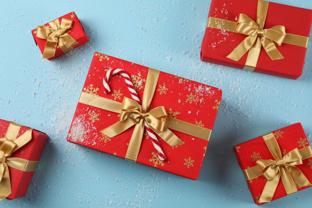 Gift boxes, candy cane and snow on blue background, top view