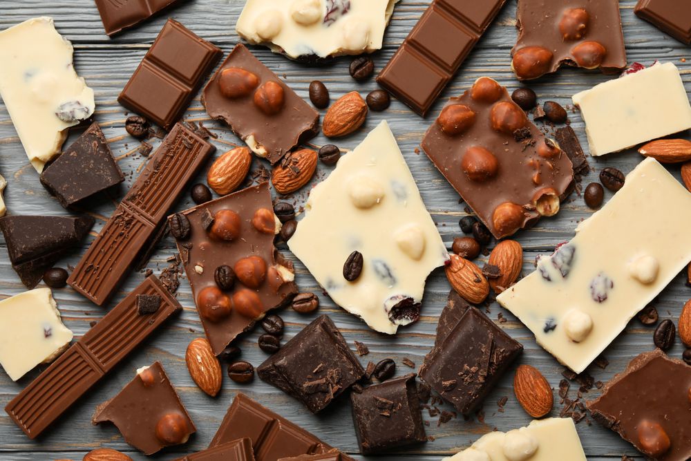 Different chocolate on gray wooden background, top view