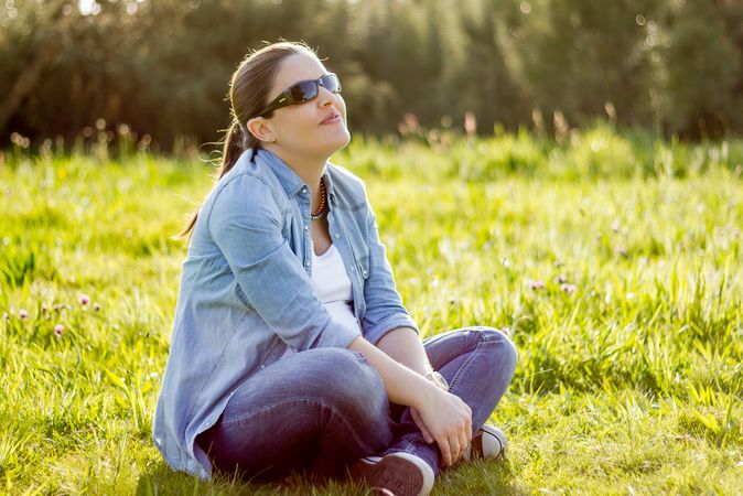 Smiling woman sunbathing sitting in a field
