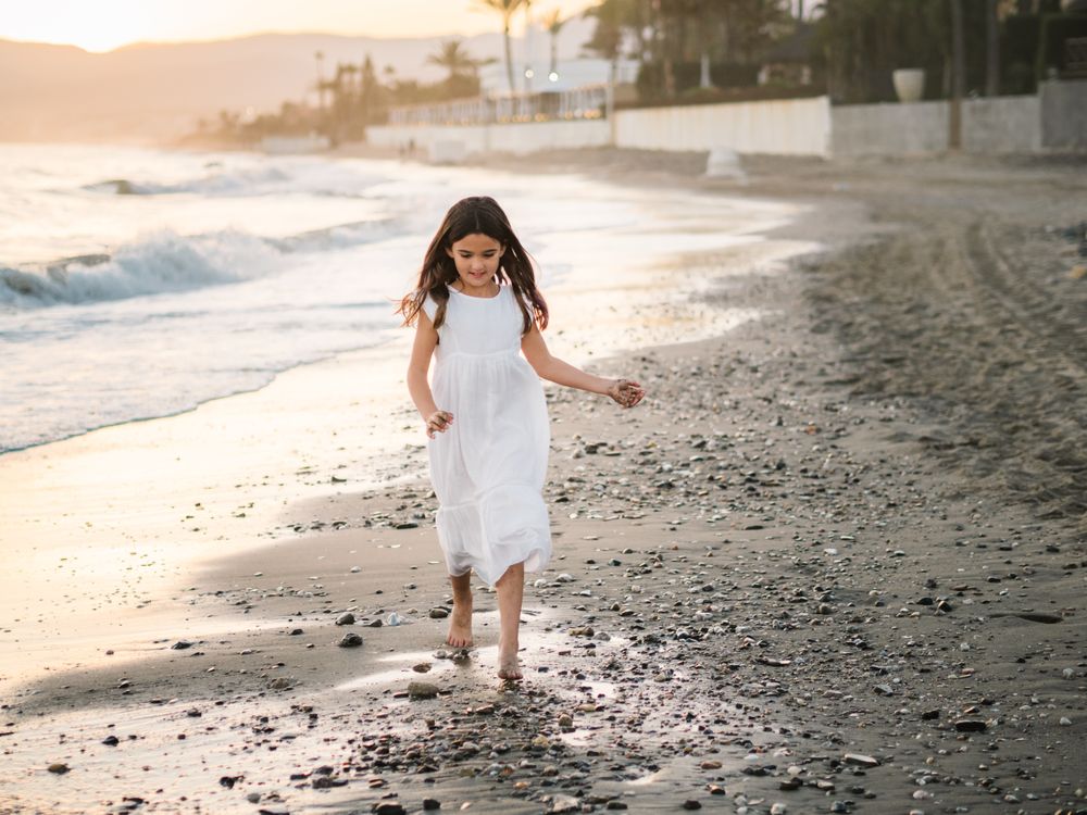Adorable girl walking on seaside at sunset