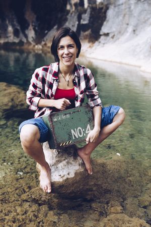 Woman with picnic case on rock in water