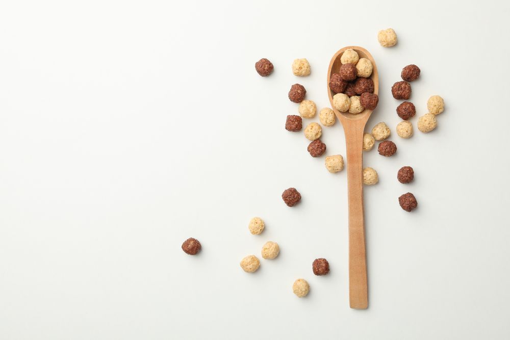 Spoon with corn balls on neutral background