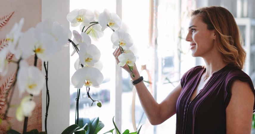 Woman in her flower shop looking at orchids