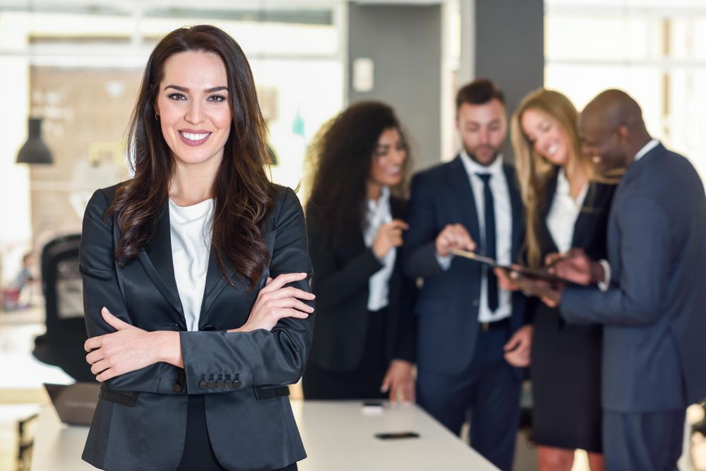 Businesswoman standing in foreground of busy office