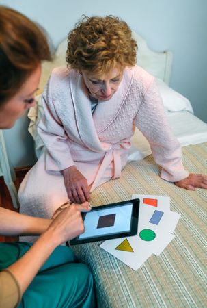 Female doctor showing geometric shapes to mature patient