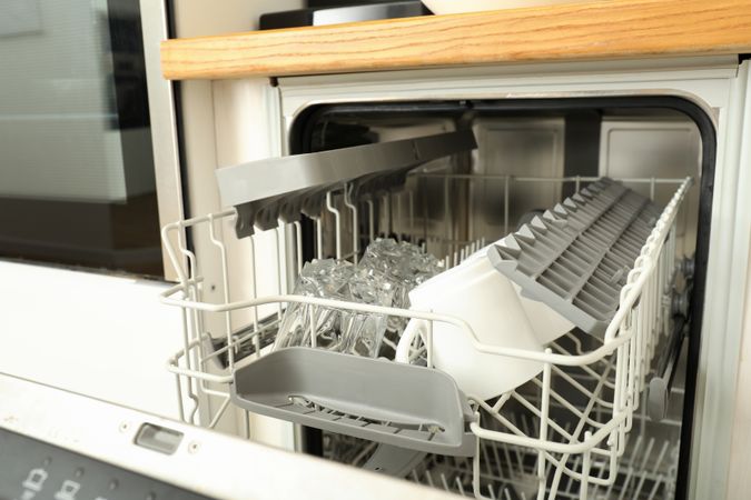 Modern open dishwasher with clean cups and glasses