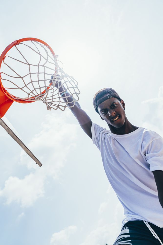 Black sportsman hanging on basketball lap