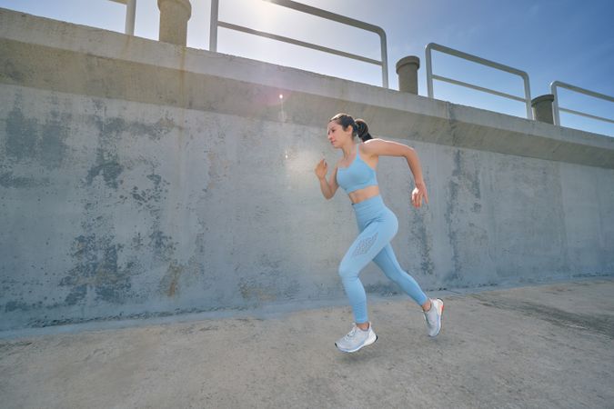 Determined runner jogging on pavement in sunshine
