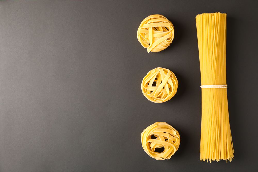 Flat lay composition with pasta on dark background, space for text