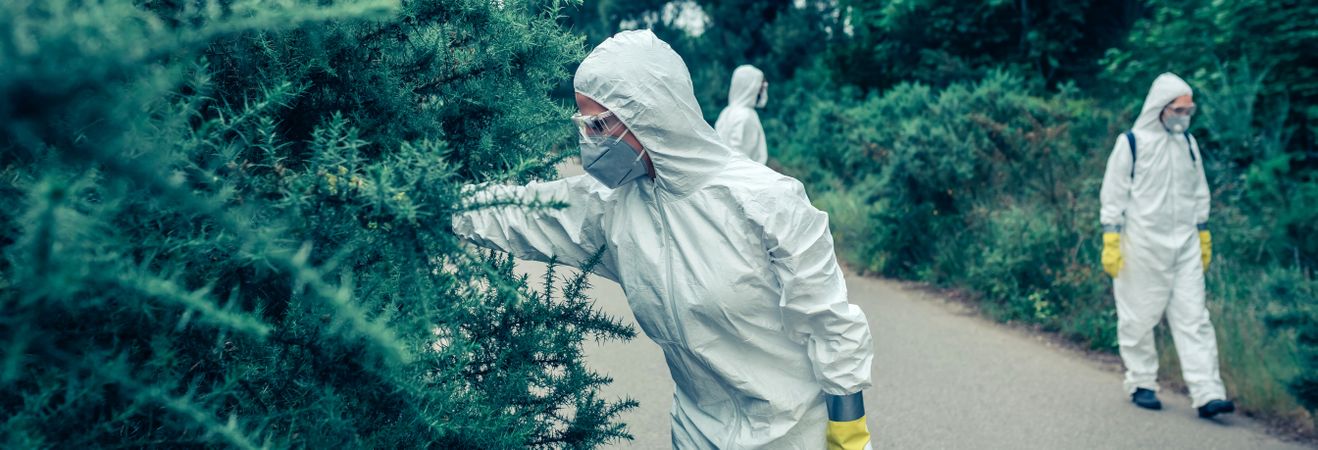 People in bacteriological protection suits looking for samples on empty road