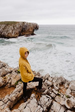 Person in yellow hoodie on stony shore