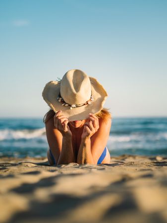 Sandy beach and woman in hat tanning