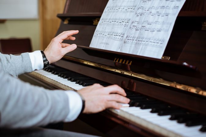 Crop male hands playing piano