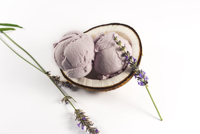 Top view of coconut shell with purple lavender ice cream and flowers