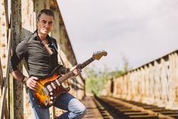 Man with guitar standing on bridge