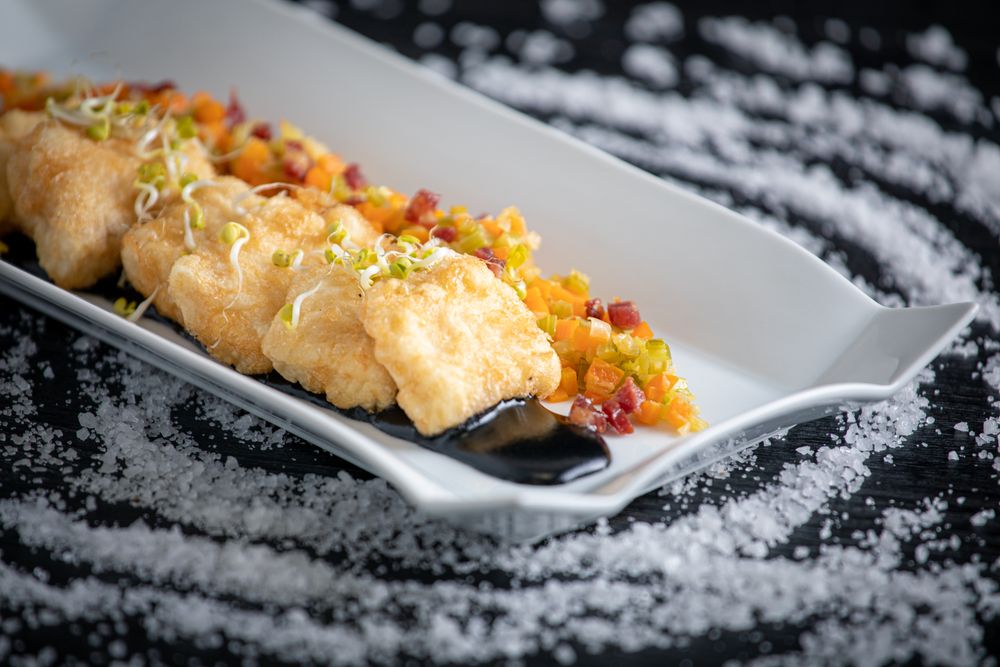 Hake breaded with matignon in rectangular plate