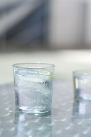Glass of water with ice on a metallic table outdoors in a sunny day