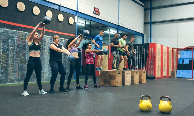 Sportswomen with kettlebells and sportsmen in background