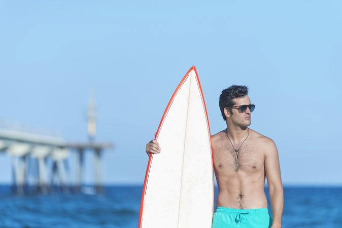 Male surfer standing with red outlined board