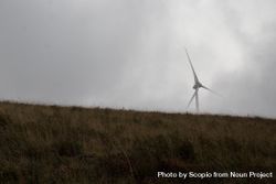 Wind turbine on green grass surrounded by fog 428O30