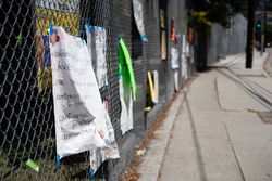 Hand lettered signs attached to chainlink fence at school during distance learning